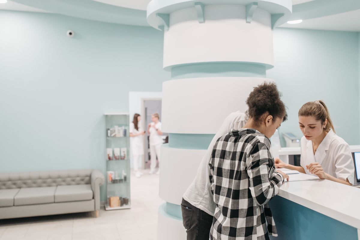 Paziente alla reception di una clinica con l’addetta all’accoglienza
