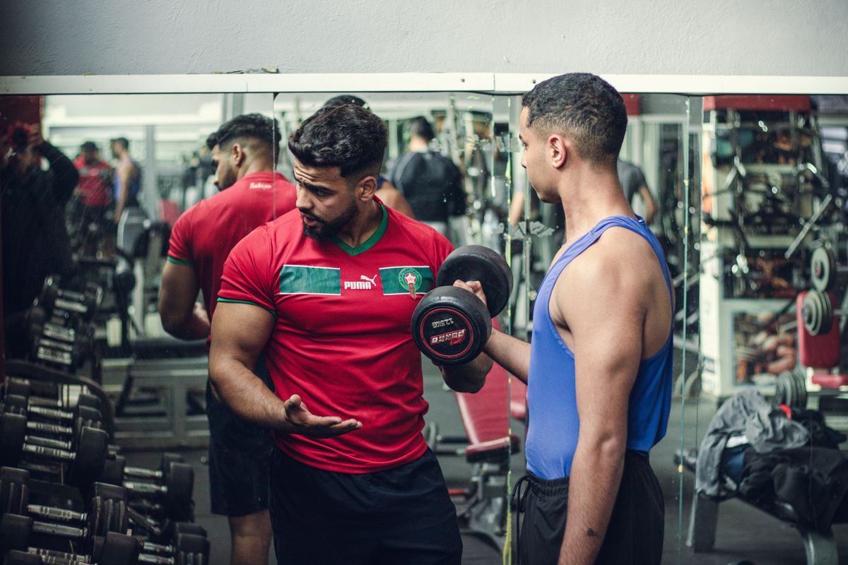 Personal trainer che segue un cliente in sala pesi